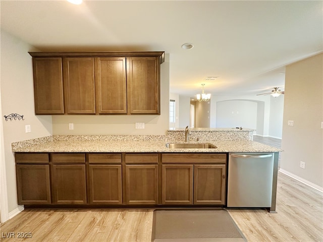 kitchen with light wood-type flooring, a sink, stainless steel dishwasher, and light stone countertops