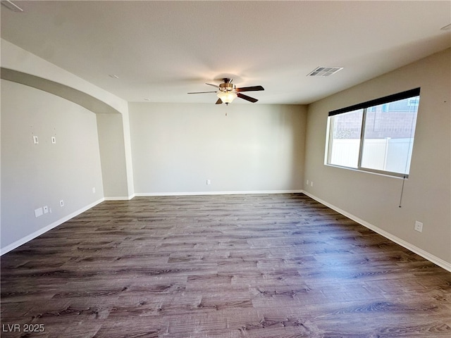 empty room with a ceiling fan, wood finished floors, visible vents, and baseboards