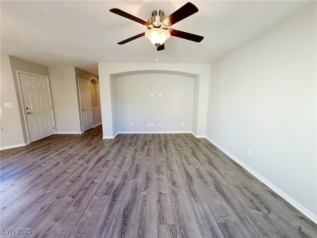 empty room with baseboards, arched walkways, a ceiling fan, and light wood-style floors