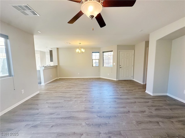 unfurnished room with visible vents, light wood-style flooring, baseboards, and ceiling fan with notable chandelier