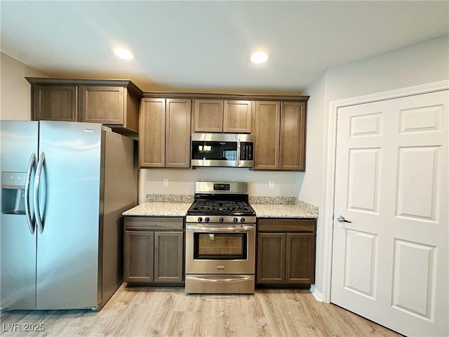 kitchen with stainless steel appliances, light stone counters, light wood-style flooring, and recessed lighting