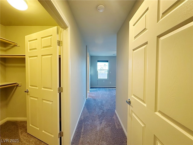 corridor with baseboards and dark colored carpet