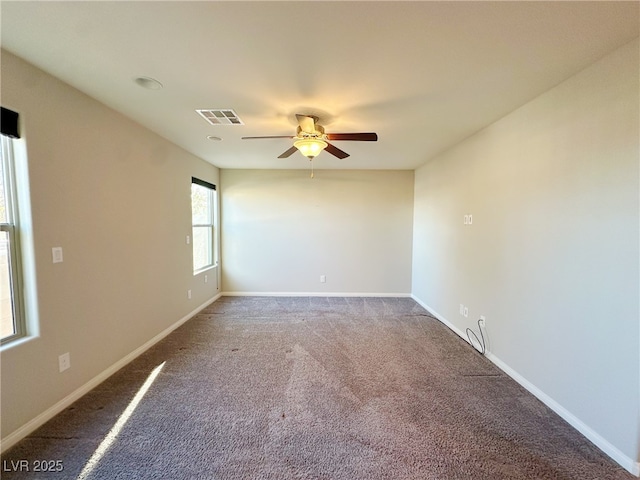 carpeted spare room featuring a ceiling fan, visible vents, and baseboards