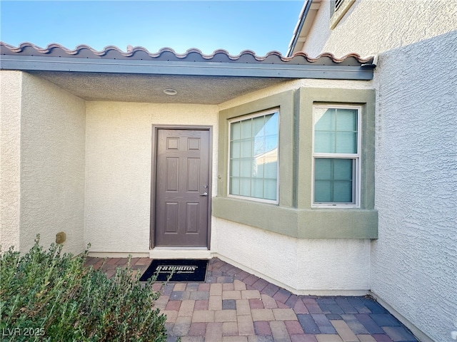 entrance to property with a tiled roof and stucco siding