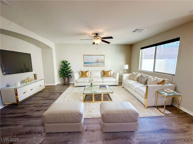 living area with dark wood-type flooring, visible vents, and baseboards