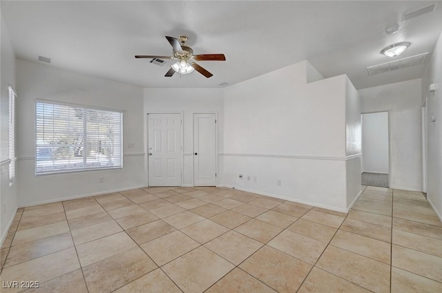 spare room with ceiling fan, light tile patterned flooring, visible vents, and baseboards