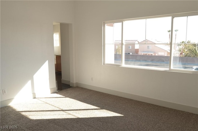 spare room featuring carpet floors and baseboards