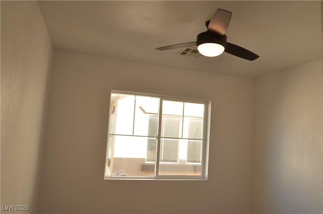 unfurnished room with a wealth of natural light, visible vents, and ceiling fan