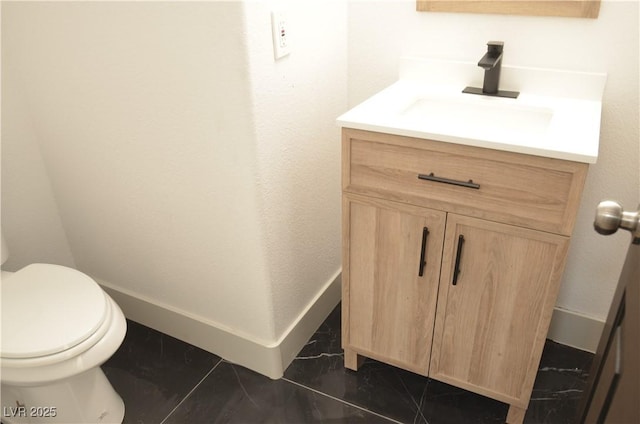 bathroom featuring toilet, marble finish floor, baseboards, and vanity