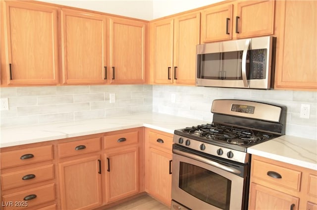 kitchen featuring appliances with stainless steel finishes, light stone countertops, and tasteful backsplash