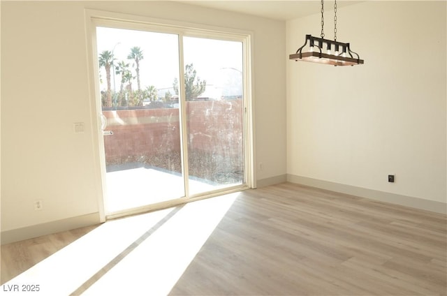 unfurnished dining area featuring wood finished floors and baseboards