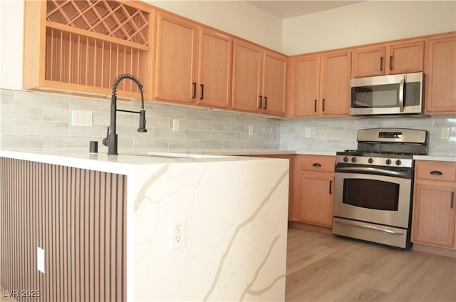 kitchen featuring stainless steel appliances, light wood-type flooring, light countertops, and tasteful backsplash