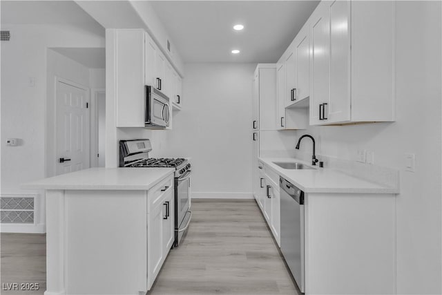 kitchen featuring a sink, stainless steel appliances, light countertops, and white cabinets