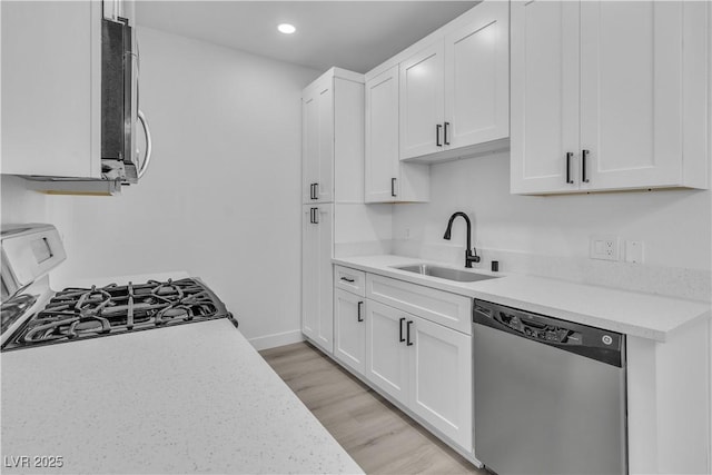 kitchen with recessed lighting, a sink, light wood-style floors, white cabinets, and appliances with stainless steel finishes