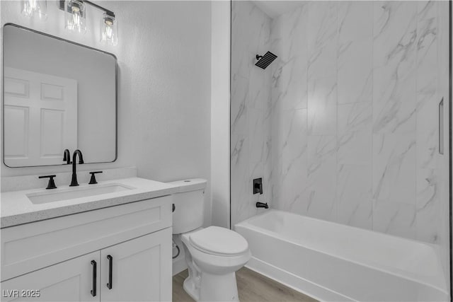 bathroom featuring wood finished floors, toilet, shower / bathing tub combination, and vanity