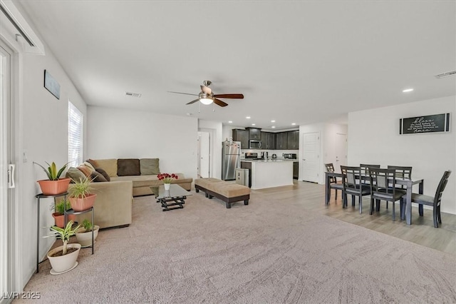 living room with recessed lighting, visible vents, ceiling fan, and light carpet