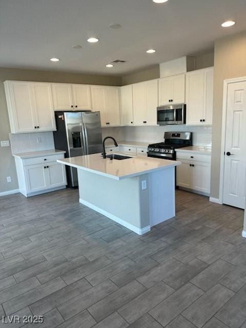 kitchen with an island with sink, white cabinetry, appliances with stainless steel finishes, and light countertops