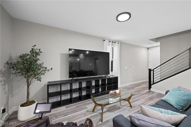 living room featuring light wood-type flooring, stairway, and baseboards