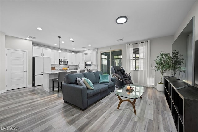 living room featuring recessed lighting, visible vents, and light wood finished floors