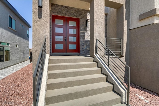 entrance to property featuring stone siding, french doors, and stucco siding