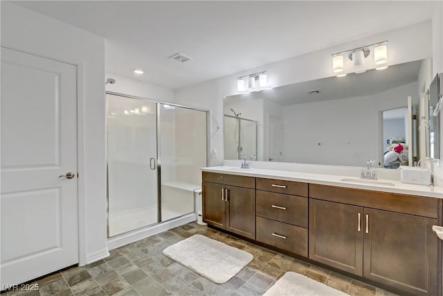 ensuite bathroom with double vanity, visible vents, ensuite bathroom, a shower stall, and a sink