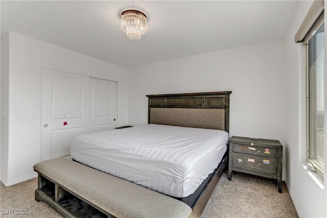 bedroom featuring a closet, light colored carpet, baseboards, and an inviting chandelier