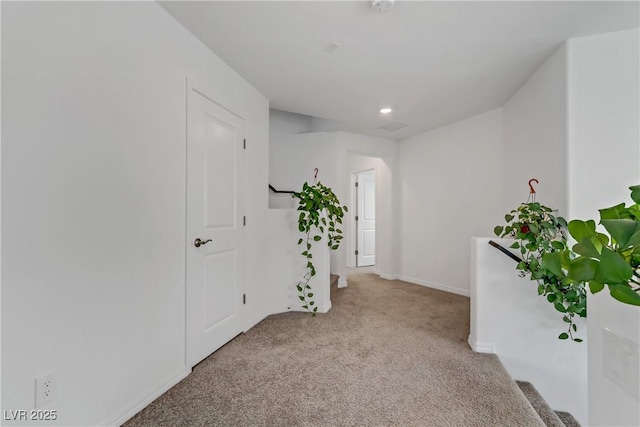 corridor featuring baseboards and light colored carpet