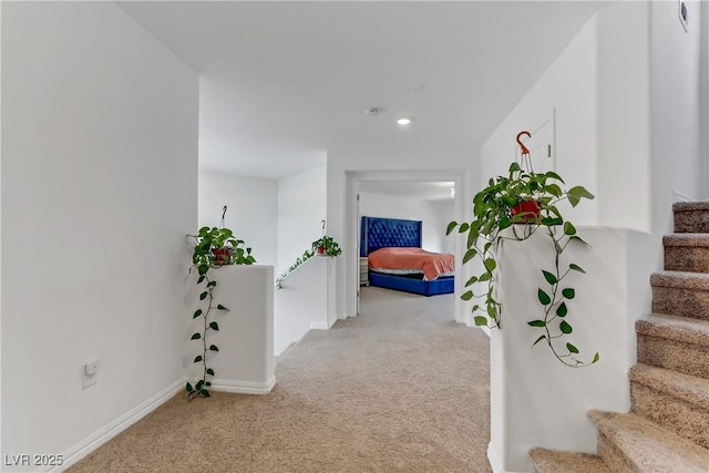 corridor with stairs, baseboards, and light colored carpet