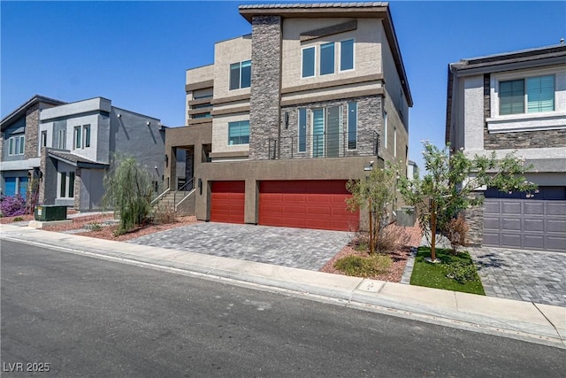 contemporary house featuring an attached garage, a residential view, decorative driveway, and stucco siding