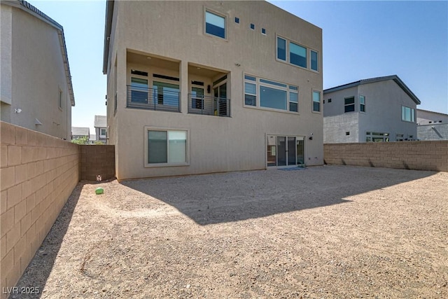 rear view of property with a fenced backyard and stucco siding