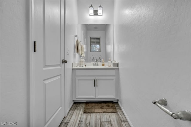 bathroom with wood tiled floor, baseboards, and vanity