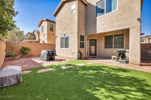 rear view of property featuring a yard, a patio, a fenced backyard, and stucco siding