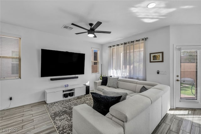 living room with wood tiled floor, visible vents, ceiling fan, and baseboards