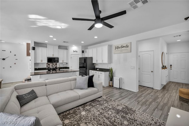 living room featuring light wood-type flooring, visible vents, a ceiling fan, and recessed lighting