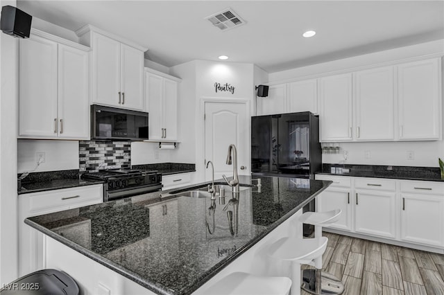 kitchen with visible vents, black appliances, and white cabinetry