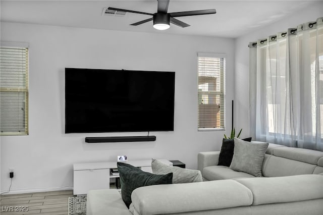 living room with light wood-type flooring, visible vents, and a ceiling fan