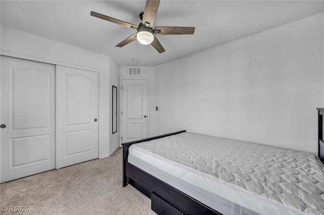 bedroom featuring light carpet, a closet, visible vents, and a ceiling fan