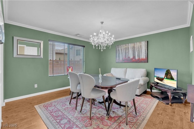 dining area with light wood-style floors, an inviting chandelier, ornamental molding, and visible vents