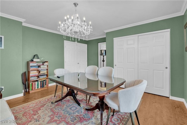 dining area with light wood finished floors, a notable chandelier, ornamental molding, and baseboards