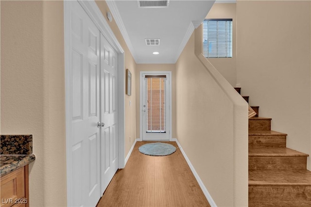 interior space featuring light wood-style flooring, baseboards, visible vents, and stairway