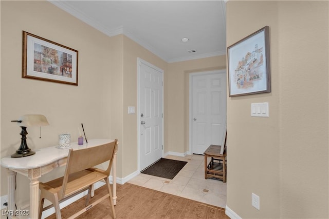foyer entrance featuring crown molding, baseboards, and light wood finished floors