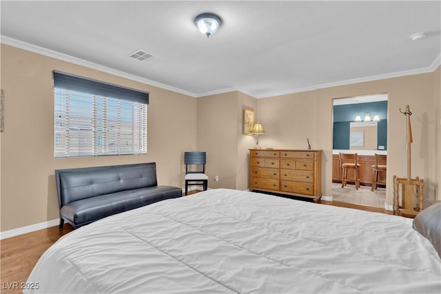 bedroom with visible vents, connected bathroom, baseboards, ornamental molding, and wood finished floors