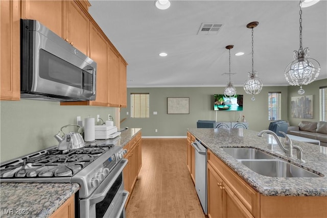 kitchen featuring light wood-type flooring, visible vents, a sink, stainless steel appliances, and crown molding