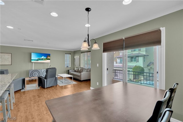 dining space with crown molding, recessed lighting, and light wood-style floors