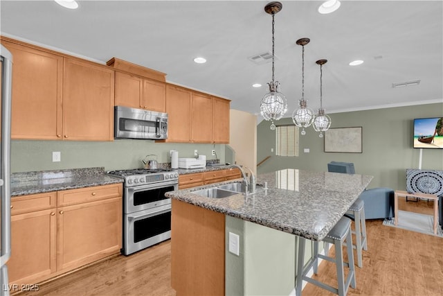 kitchen with light wood-style flooring, visible vents, a breakfast bar area, stainless steel appliances, and a sink