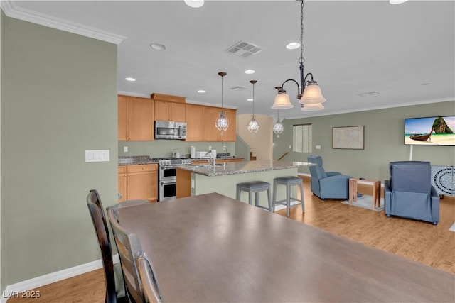 dining space with an inviting chandelier, ornamental molding, visible vents, light wood finished floors, and baseboards