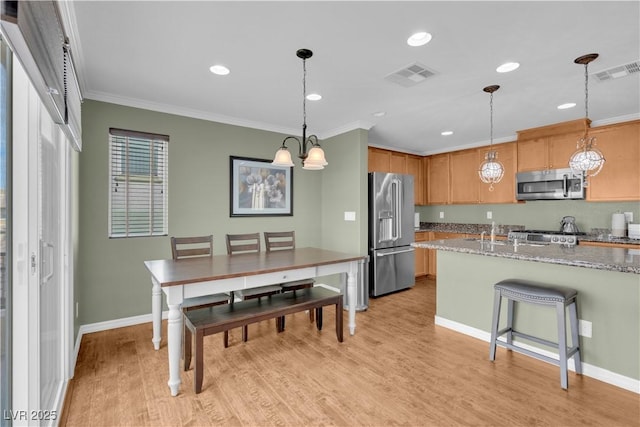 kitchen featuring light wood-type flooring, stainless steel appliances, visible vents, and ornamental molding