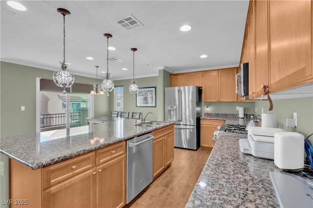 kitchen featuring visible vents, light wood-type flooring, an island with sink, stainless steel appliances, and a sink