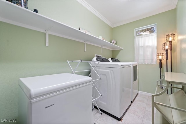 clothes washing area featuring ornamental molding, washing machine and dryer, light tile patterned flooring, baseboards, and laundry area