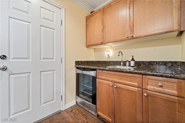 kitchen with wine cooler, dark stone counters, ornamental molding, dark wood-style floors, and a sink